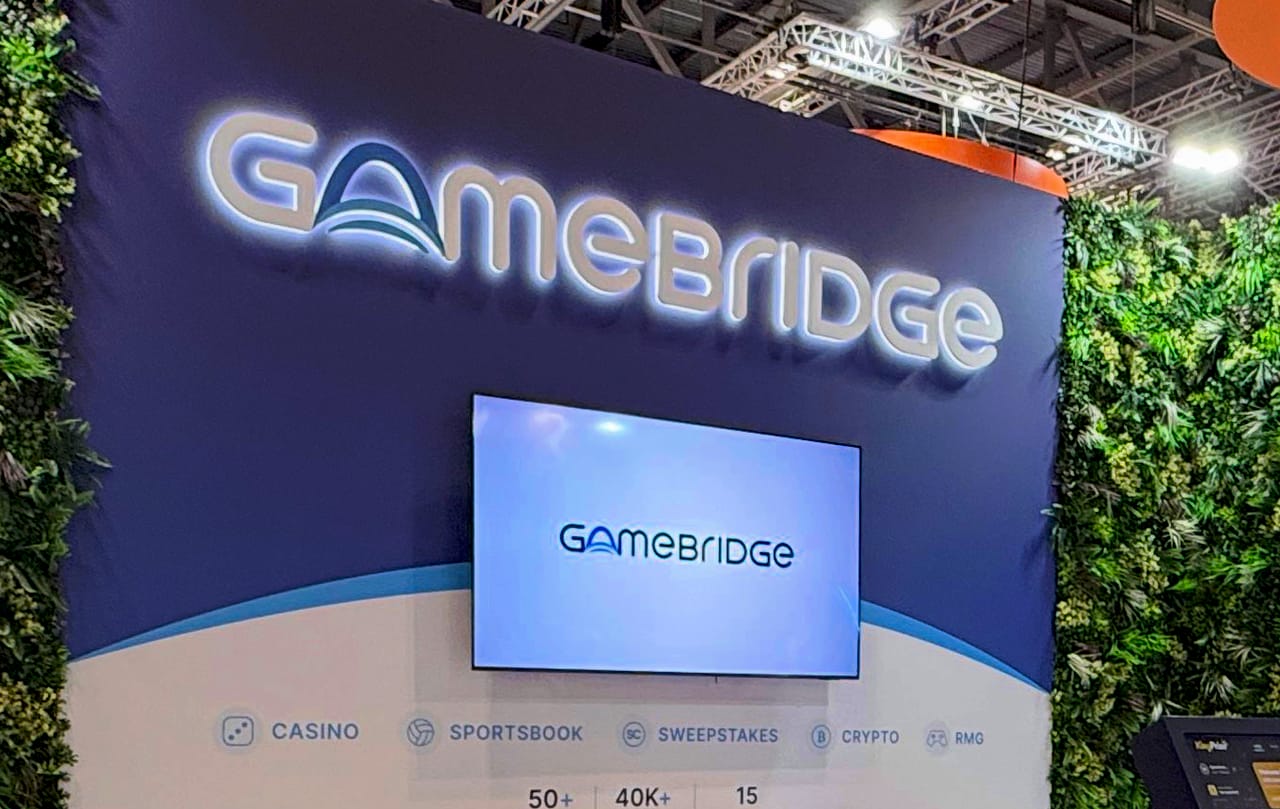 Close-up of the GameBridge wordmark and demo screen on the stand's back wall